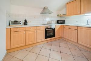 a kitchen with wooden cabinets and a tile floor at Ferienwohnung Seilbahn in Sankt Gilgen