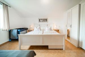 a white bedroom with a white bed with pink pillows at Ferienwohnung Seilbahn in Sankt Gilgen