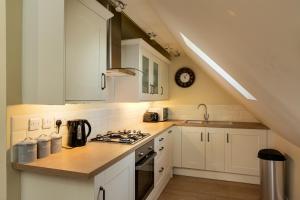 a kitchen with white cabinets and a stove top oven at Self contained accommodation near Delamere forest in Oakmere