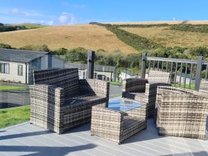 un patio con sillas y una mesa de cristal en una terraza. en Mawgan Pads Mawgan Porth, en Mawgan Porth