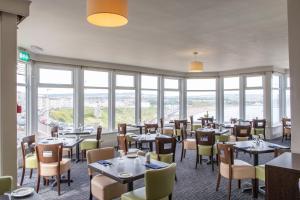 um restaurante com mesas, cadeiras e janelas em The Norbreck Hotel by Compass Hospitality em Scarborough