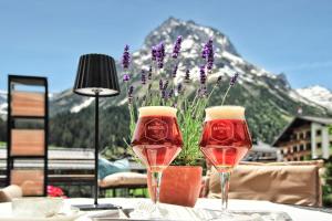 two glasses of wine on a table with a mountain at Haldenhof in Lech am Arlberg