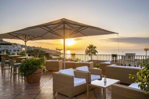 een patio met tafels en stoelen en een parasol bij Grand Hotel La Favorita in Sorrento