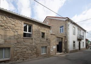 een oud stenen huis met een wit gebouw bij Casa Moiano in Oliveira do Hospital