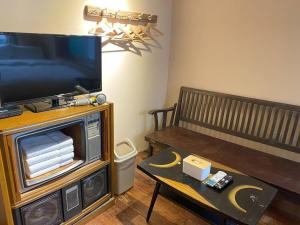 - un salon avec une télévision, un banc et une table dans l'établissement Tainan MacArthur Homestay, à Tainan