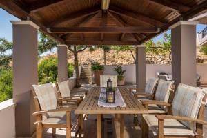 una mesa de comedor al aire libre y sillas bajo una pérgola de madera en Tholos Apartments, en La Canea