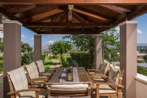 una mesa de comedor al aire libre y sillas bajo una pérgola de madera en Tholos Apartments, en La Canea