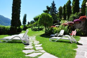 drie stoelen zittend op het gras in een tuin bij Charme Hotel Nevada in Molveno