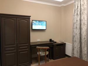 Zimmer mit einem Schreibtisch und einem TV an der Wand in der Unterkunft Atlant Hotel in Uschhorod