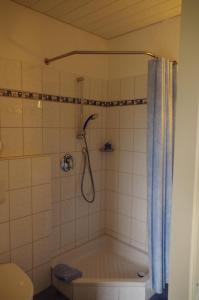 La salle de bains est pourvue d'une baignoire et d'une douche avec rideau de douche. dans l'établissement Hotel Heidetraum, à Schneverdingen