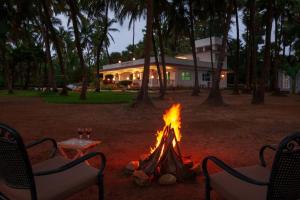 eine Feuerstelle vor einem Haus mit zwei Stühlen in der Unterkunft StayVista's Villa Bharat - Beachfront serenity with A spacious lawn in Mumbai