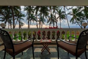 einen Tisch und Stühle auf einem Balkon mit Palmen in der Unterkunft StayVista's Villa Bharat - Beachfront serenity with A spacious lawn in Mumbai