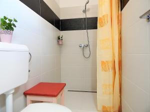 a bathroom with a shower with a toilet and a red stool at Bogácsa Apartman in Bogács