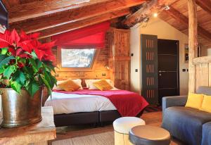 een slaapkamer met een bed met rode lakens en een bank bij Locanda4 in Valtournenche