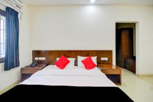 a bedroom with a large bed with red pillows at Mayfair Service Apartments in Pīlamedu