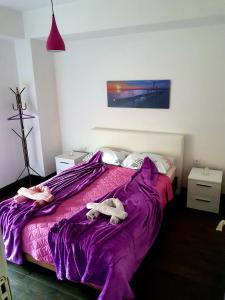 1 dormitorio con 1 cama morada y 2 toallas en Grkov Apartment, en Skopje