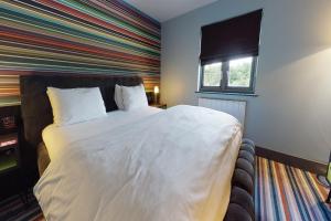 um quarto com uma cama grande e uma parede listrada em Village Hotel Manchester Bury em Bury