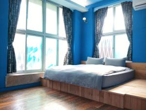 - une chambre avec des murs bleus et un lit avec des fenêtres dans l'établissement Tainan MacArthur Homestay, à Tainan