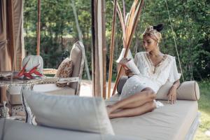 kobieta siedząca na huśtawce czytająca książkę w obiekcie Khwan Beach Resort - Luxury Glamping and Pool Villas Samui - Adults Only - SHA Extra Plus w mieście Mae Nam