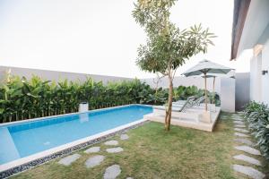 una piscina con tavolo e ombrellone di Vasudha Hostel Canggu a Canggu