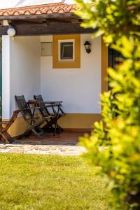 een patio met 2 stoelen en een tafel op een huis bij Monte Das Alpenduradas in Zambujeira do Mar