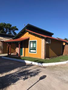 una pequeña casa amarilla con techo rojo en Casa com piscina para família, en Florianópolis