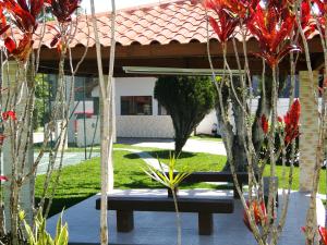 un banco en un patio con árboles y flores rojas en Casa com piscina para família, en Florianópolis