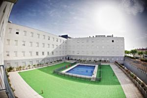 um grande edifício com uma piscina em frente em Apartamentos Vértice Sevilla Aljarafe em Bormujos