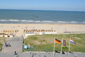 een strand met een promenade en een strand met mensen bij Strandhotel Golfzang in Egmond aan Zee