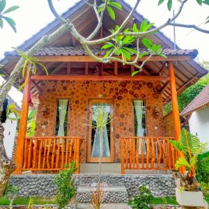 uma casa com um alpendre em madeira e um edifício em Grealeen Cottages em Nusa Penida