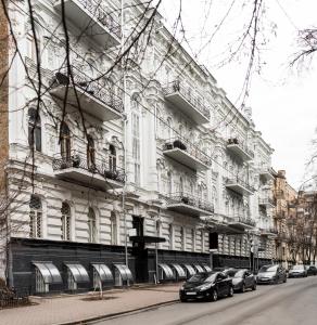 un gran edificio blanco con coches estacionados frente a él en Globe Runner Hostel, en Kiev