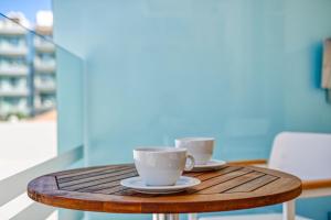 dos tazas de café sentadas en una mesa de madera en Island Boutique Hotel, en Rodas