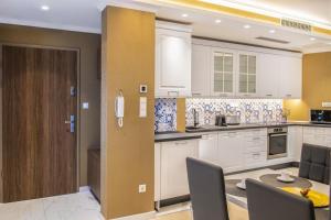 a kitchen with white cabinets and a table and chairs at Spa Residence Carbona Apartment 105 in Hévíz