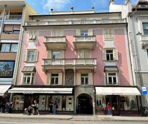 een roze gebouw waar mensen voor lopen bij Apartment Emilie with parking historic city center in Merano