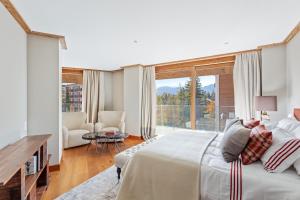 een slaapkamer met een groot bed en een groot raam bij Sport Club Residences & Spa in Crans-Montana