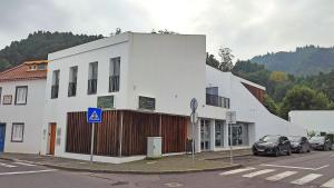 un edificio blanco con coches estacionados frente a él en Atlantic 3 Bicas - Furnas, en Furnas