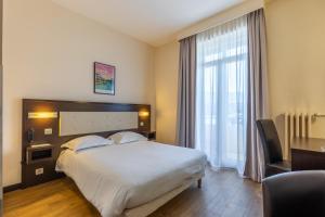 a hotel room with a bed and a desk and a window at Hôtel Le Florin in Rennes