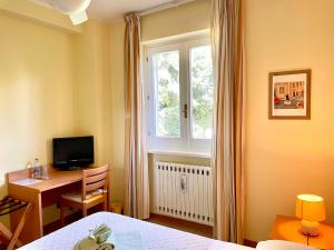 a bedroom with a bed and a desk and a window at Inn Rome B&B in Ciampino