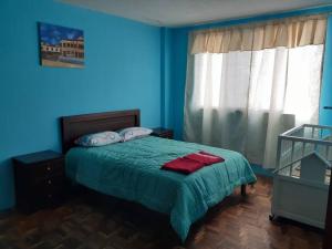 een blauwe slaapkamer met een bed met een groene deken bij Amplio y cómodo departamento. in Loja