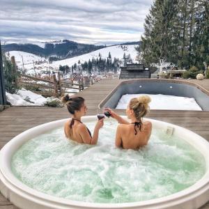 two women are sitting in a jacuzzi tub at Stara Pravda Villas in Bukovel