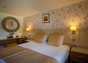 - une chambre d'hôtel avec un lit et un miroir dans l'établissement Royal Victoria Hotel Snowdonia, à Llanberis