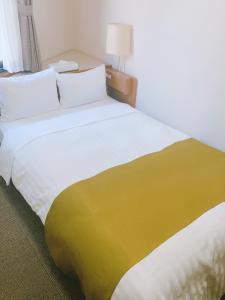 un grande letto con una coperta gialla e bianca di Fuchu Urban Hotel a Fuchū