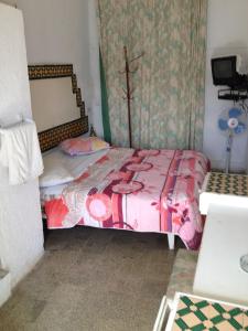 - une petite chambre avec un lit et une couette rose dans l'établissement Hôtel Sindbad, à Houmt Souk