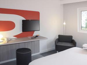 Pokój z biurkiem, krzesłem i telewizorem w obiekcie ibis Styles Beauvais w Beauvais