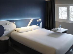 sypialnia z dużym białym łóżkiem i oknem w obiekcie ibis Styles Beauvais w Beauvais