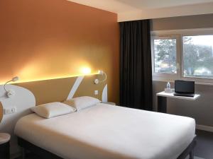 sypialnia z białym łóżkiem i oknem w obiekcie ibis Styles Beauvais w Beauvais