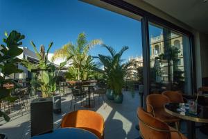 eine Terrasse mit Tischen und Stühlen und einem großen Fenster in der Unterkunft Soho Boutique Catedral in Sevilla