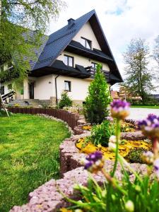 a house with a black roof and a yard with flowers at Lawenda in Białka Tatrzanska