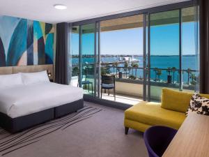 sypialnia z łóżkiem i widokiem na ocean w obiekcie Novotel Geelong w mieście Geelong