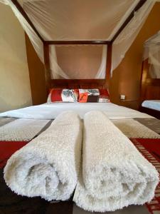 uma cama numa tenda com dois cobertores brancos em Gorilla African Guest House em Entebbe